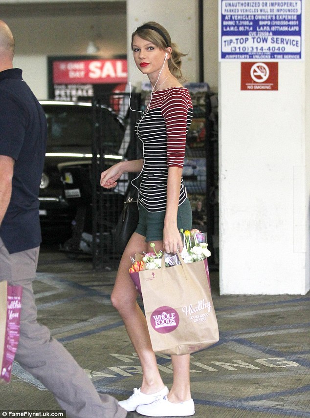 No personal shoppers? The 5ft 10in beauty - rocking her signature red lipstick - purchased vegetables and a pretty bouquet