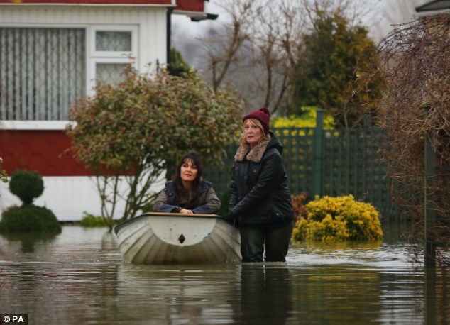 Christine Baker, right, helps Sue Hyland through the flood waters at Abbey Fields caravan park in Chertsey, Surrey following floods last week