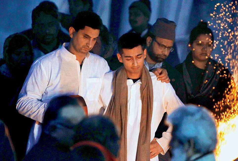 The grieving 21-year-old son
of Sunanda Pushkar, Shiv,
being consoled by family
members near her pyre