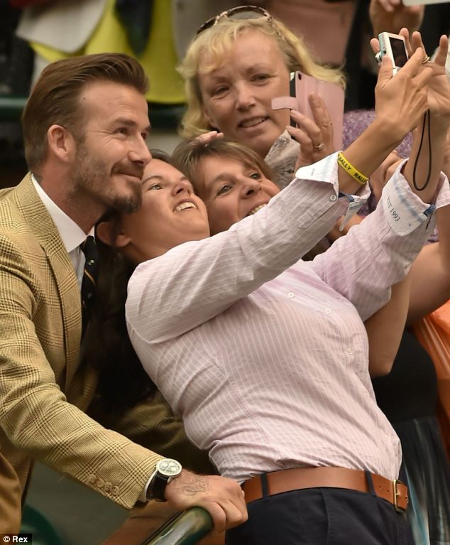 Selfie hat-trick: David Beckham poses for a photo with three adoring fans during a break at Wimbledon today