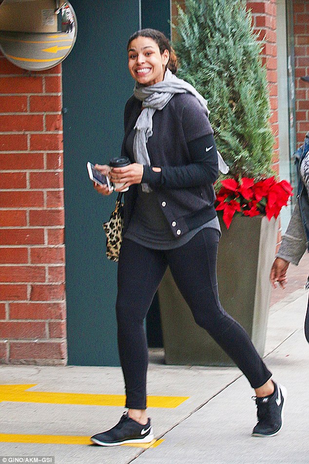 Finishing touches: She kept warm in a dark athletic jacket with a scarf round her neck, while carrying an animal print purse and a cup of coffee