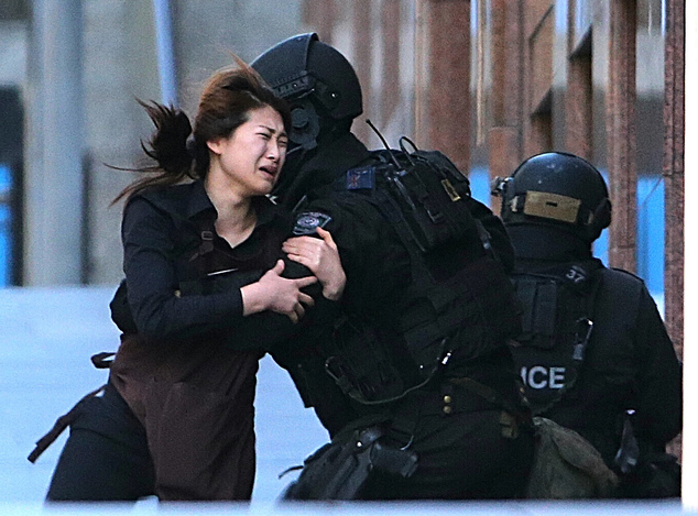 A hostage runs to armed tactical response police officers for safety after she escaped from a cafe under siege at Martin Place in the central business distri...