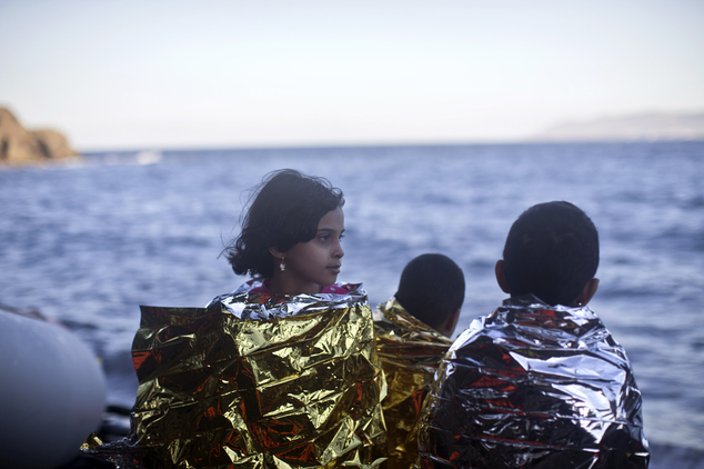 Children wrapped in emergency blankets stand on a beach as they have disembarked from a small boat on the northern shore of Lesbos, Greece, Monday, Nov. 2, 2...