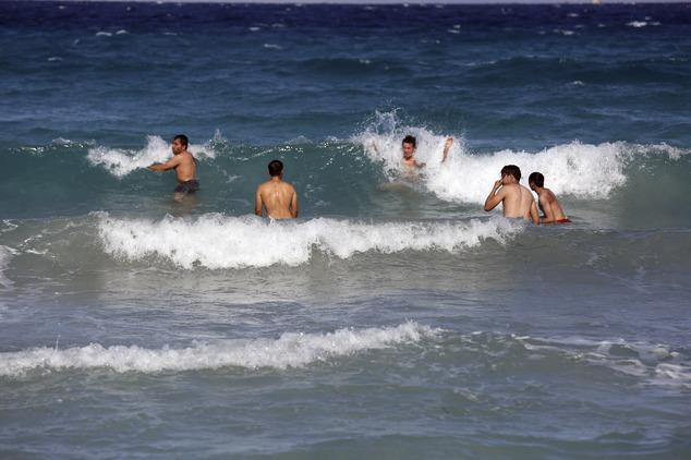 Migrants and refugees swim as they as they pass time before trying to cross to the Greek Island of Chios,, near Cesme, Turkey, Sunday, Nov. 1, 2015. Greek au...