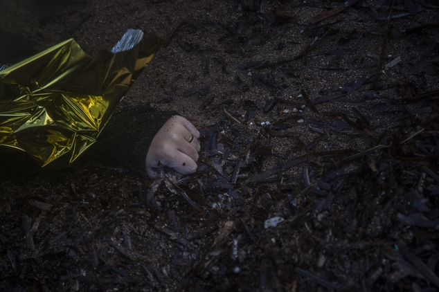 The hand of an unidentified woman wearing a wedding ring is seen on a beach after the lifeless body washed up on the shoreline at the village of Skala, on th...