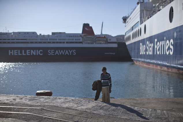 An Afghan man stands in the sun in order to dry his clothes at the port of Mytilene on the island of Lesbos, Greece, Monday, Nov. 2, 2015. More than 300,000 ...