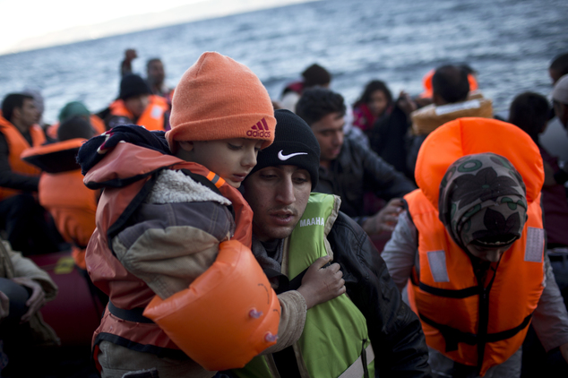 A man carries a child as they disembark a rubber boat on the northern shore of Lesbos, Greece, Monday, Nov. 2, 2015. The number of smuggling boats crossing o...