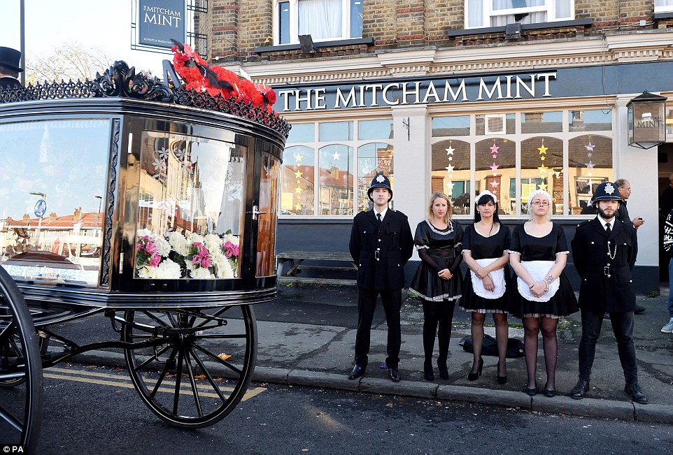 Actors dressed as policeman and maids stand outside the Mitcham Mint pub this afternoon as Cynthia Payne was laid to rest