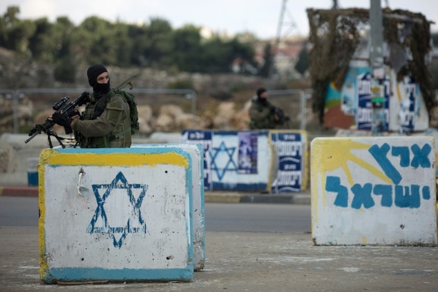 An Israeli soldier stands guard at the Gush Etzion junction in the Israeli-occupied West Bank on the main road between Jerusalem and Hebron on December 2, 2015