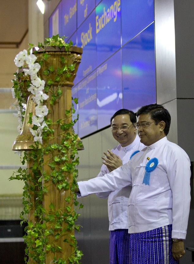 Myanmar's Vice President Nyan Tun, right ceremonially rings the bell as Maung Maung Thein, Deputy Minister of Finance and Revenue, left applauds during the o...