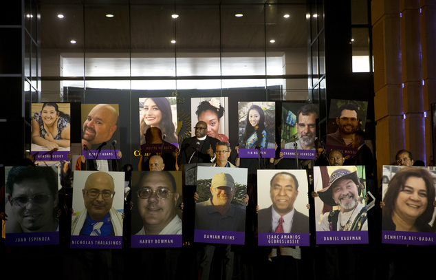 San Bernardino County employees hold up photos of the San Bernardino shooting victims during a candlelight vigil on Monday, Dec. 7, 2015, in San Bernardino, ...