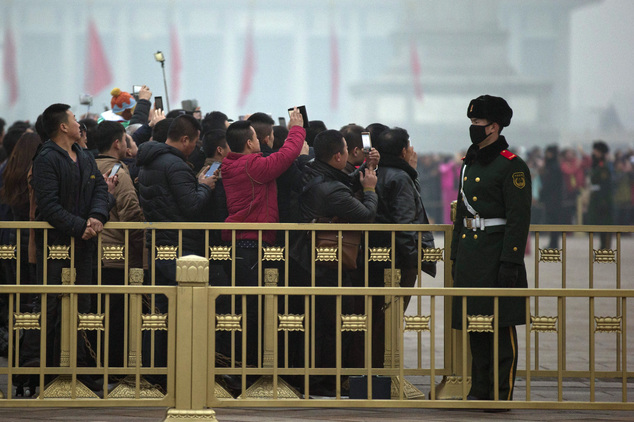 A Chinese military policeman wears a mask to protect against the pollution during the daily flag lowering ceremony on Tiananmen Square in Beijing, China, Wed...