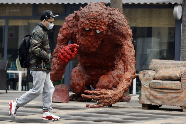 A man wears a mask to protect against the pollution as he walks past a sculpture in Beijing, China, Wednesday, Dec. 9, 2015. Unhealthy smog hovered over down...