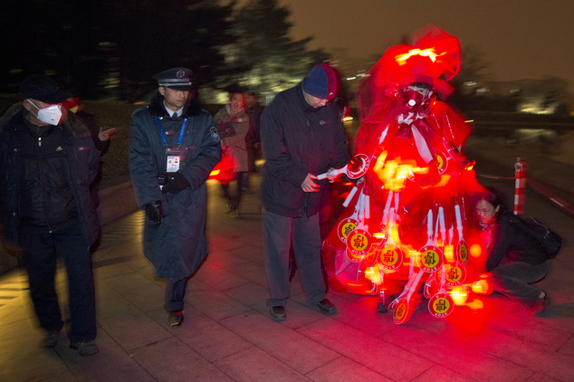 Performance artist Kong Ning wears a gown with glowing red light and stop signs to raise awareness of the smog enveloping Beijing, China, Wednesday, Dec. 9, ...