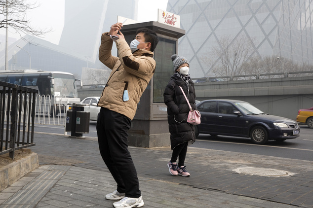 Pedestrians wear masks for protection against the pollution in Beijing, China, Wednesday, Dec. 9, 2015. Unhealthy smog hovered over downtown Beijing as limit...