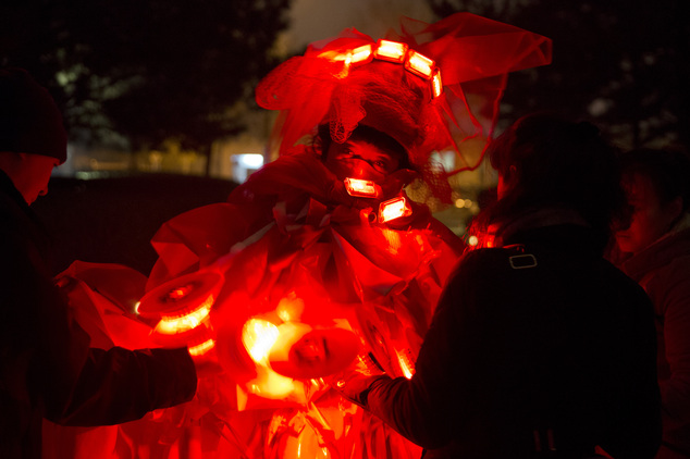 Performance artist Kong Ning wears a gown with glowing red light and stop signs to raise awareness of the smog enveloping Beijing, China, Wednesday, Dec. 9, ...