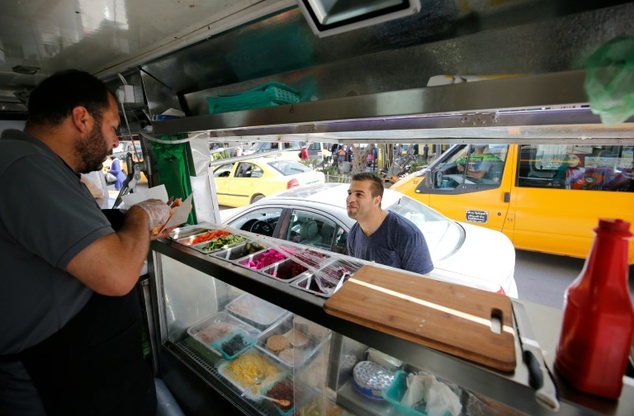 Palestinian Khaldun serves food to a customer at his food truck called "Food Train" which he runs with his friend Abderrahman in the West Bank city of Ramall...