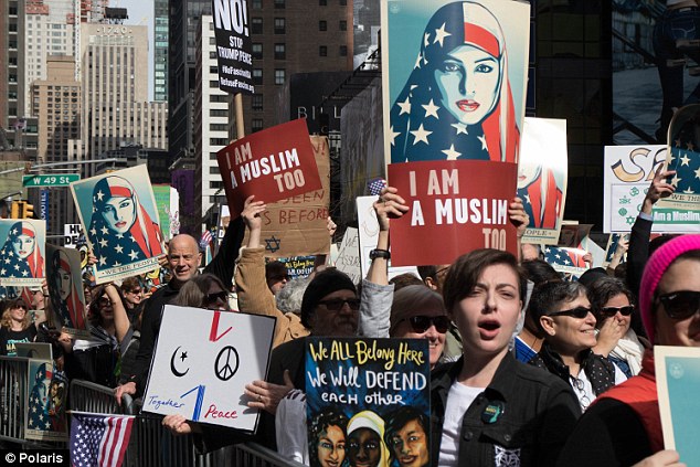 People carry posters during a rally in support of Muslim Americans and protest of President Donald Trump's immigration policies in Times Square