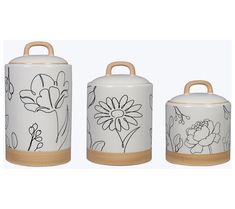 three ceramic canisters with flowers painted on the front and sides, one has a wooden handle