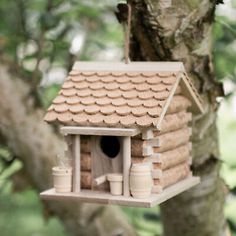 a birdhouse hanging from a tree in the woods with its roof made out of clay