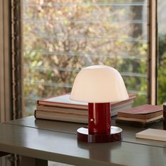 a lamp sitting on top of a wooden table next to a book and cup filled with coffee