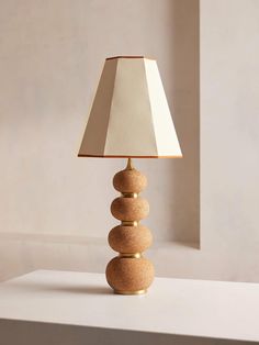 a lamp that is sitting on top of a white table with a beige shade over it