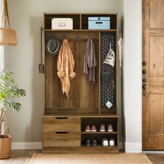 an entryway with a coat rack and shoes on the floor next to a potted plant