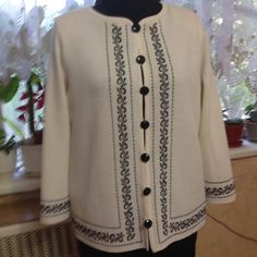 a woman's white jacket with black trimmings and buttons on the front