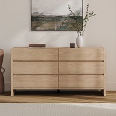 a large wooden dresser sitting on top of a hard wood floor next to a vase