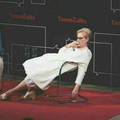 a woman sitting in a chair on top of a red carpet