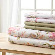 a stack of four sheets sitting on top of a wooden table next to a window