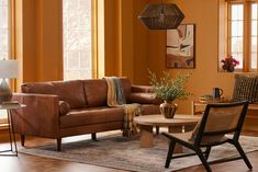 a living room with orange walls and furniture in the corner, including a brown leather couch