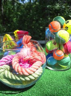 two clear bowls filled with balls and rope on top of green artificial grass covered ground