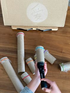 a person is holding an object in front of several rolls of toilet paper on a table