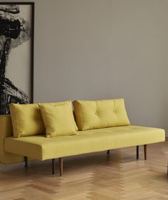 a yellow couch sitting in front of a painting on the wall next to a coffee table