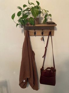 a coat rack with two coats and a purse hanging from it's hooks on the wall