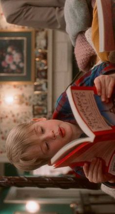 a young boy is reading a book in the living room