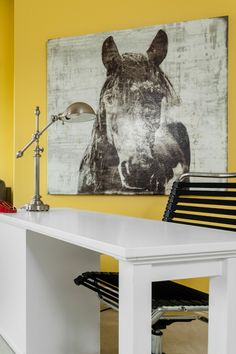 a white desk with a black chair next to it and a horse painting on the wall