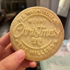 a hand holding a cookie that says we wish you a merry christmas at miller's