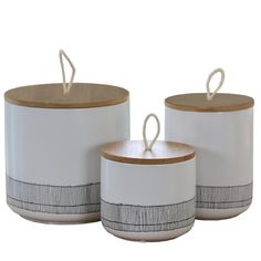 three white canisters with wooden lids and handles