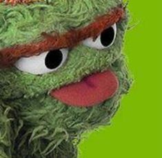 the muppet is wearing a red hat and green shirt with orange trims on it's head