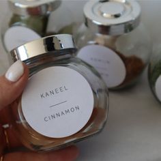 a person holding up a jar filled with cinnamons on top of a white table