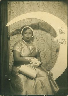 an old black and white photo of a woman sitting in front of a crescent moon