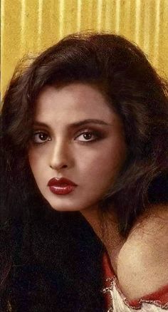 an old photo of a woman with long hair and red lipstick on her face, wearing a white dress