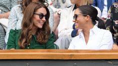 two women sitting next to each other at a tennis match