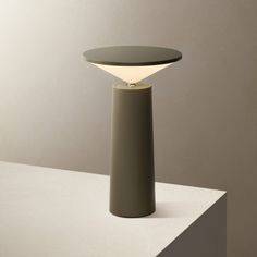 a table lamp sitting on top of a white counter next to a gray wall and floor