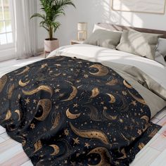 a bed with a black and gold blanket on top of it next to a potted plant