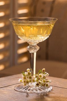 a wine glass sitting on top of a wooden table next to a vase filled with flowers