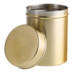 a gold canister with a lid and an intricate design on the side, sitting next to a white background