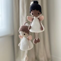 two crocheted angel mobiles hanging from a string in front of a window